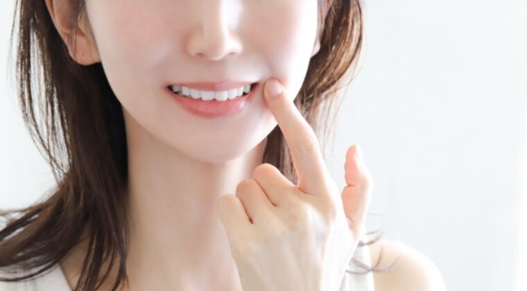 口元を指さす女性